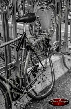 black and white of bicycle chained to metro station railing