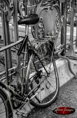 black and white of bicycle chained to metro station railing